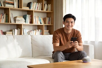 Fototapeta premium Man sitting on couch using smartphone