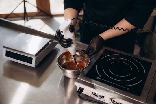 Chef blending caramel with immersion blender in kitchen