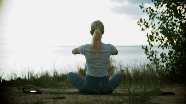 Woman Practicing Yoga in Lotus Pose by the Sea. Meditation and Relaxation on Coast. Mental Health