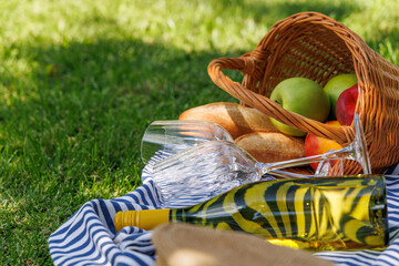 Obraz premium Picnic basket with wine, fruits, and baguette on a sunny green meadow