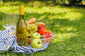 Obraz premium Picnic with wine, fruits, and baguette on a green meadow