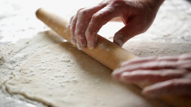 A woman in her kitchen rolls out dough to prepare dumplings with cottage cheese