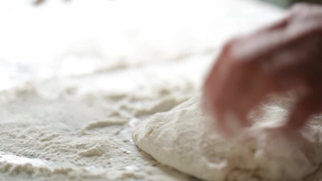 A woman kneads dumpling dough with her hands in her kitchen