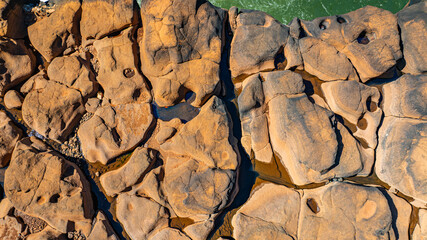 Fototapeta premium Clear mountain stream flowing over rocks and pebbles captured from above by a drone. The image showcases the beauty of freshwater movement, natural textures, and a serene outdoor environment.