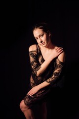 Fototapeta premium A girl in a black dress, photo shoot on a black background