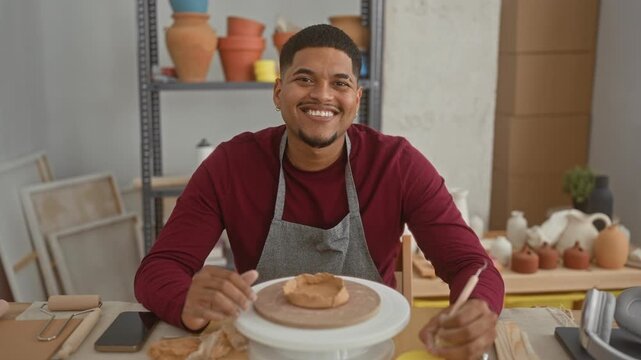 Hispanic man with beard shaping clay on a pottery wheel with hands, smiling in a studio; craft creativity contentment.