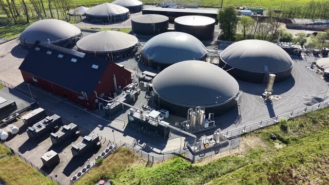 Detailed drone orbit around large biogas digester domes and specialized gas processing equipment at a facility near Hammel, Denmark.