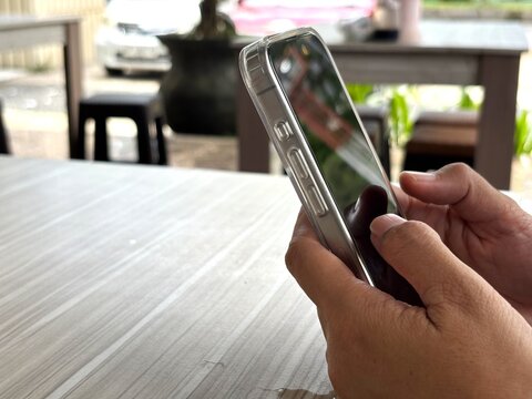 An Asian woman holds a cell phone with a specially designed tempered glass screen protector that uses polarizing optical coating technology to make it difficult to spy on.