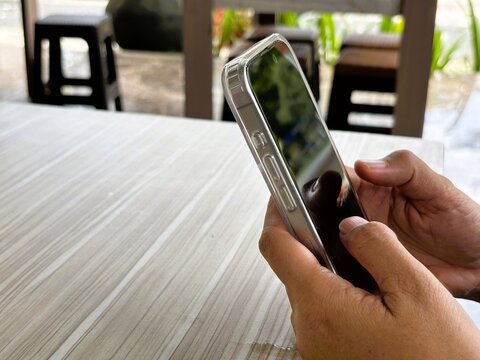 An Asian woman holds a cell phone with a specially designed tempered glass screen protector that uses polarizing optical coating technology to make it difficult to spy on.