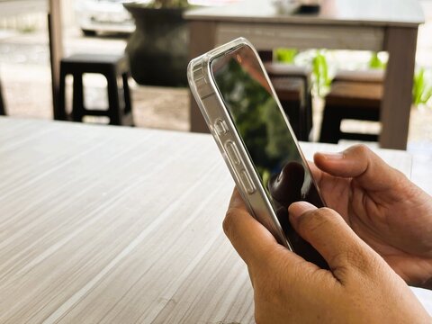 An Asian woman holds a cell phone with a specially designed tempered glass screen protector that uses polarizing optical coating technology to make it difficult to spy on.