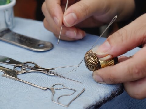 Hands sewing fabric with needle and tools