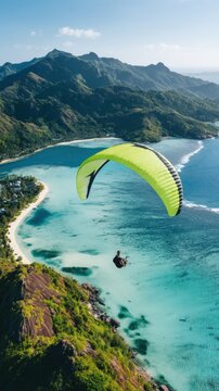 Aerial view of paraglider with bright lime green canopy over tropical coastline and blue ocean