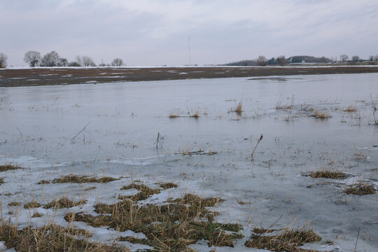 Vast flooded field under overcast cloudy sky, gloomy autumn or spring weather