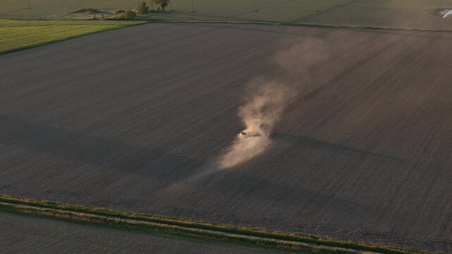 Tractor plowing a field at sunset in the Po Valley, Italy