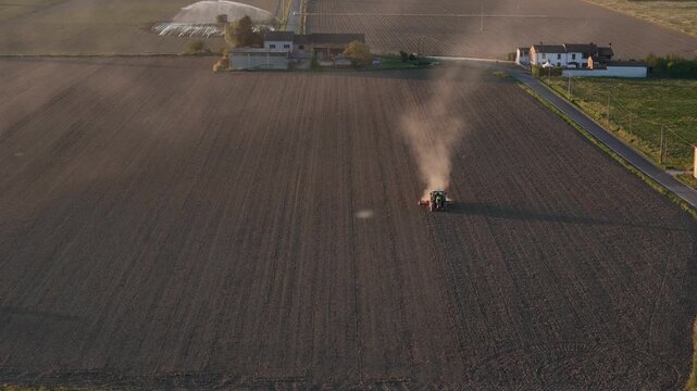 Tractor plowing a field at sunset in the Po Valley, Italy