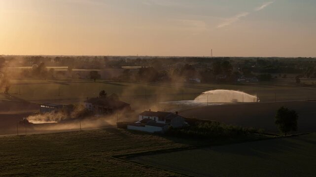 Golden hour sunset over Po Valley with tractor and irrigation systems