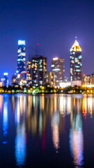 Fototapeta premium Blurred Cityscape Lights Reflecting on Lake Water at Night