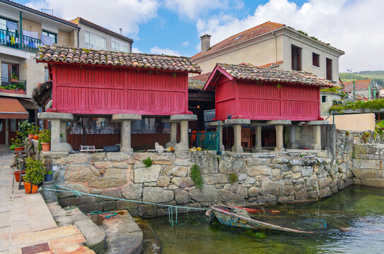 Traditional red wooden horreos on stone pillars by the sea in the fishing village of Combarro Galicia Spain