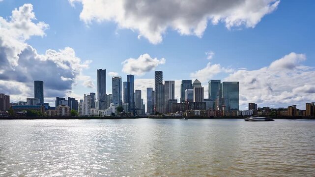 A captivating time-lapse captures the dynamic interplay of clouds and sunlight over the iconic canary wharf skyline and thames river.