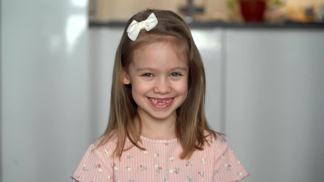 Portrait of little happy toothless girl looks at camera and laughs. Baby milk teeth change