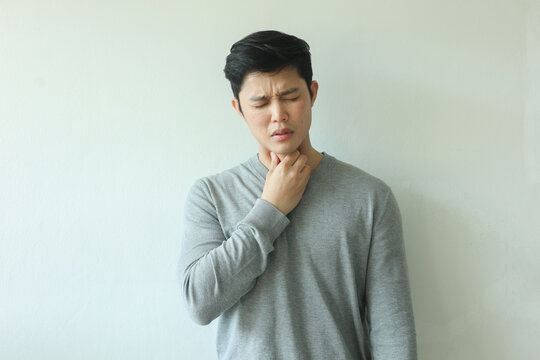 close up young asian man use hand to massage on neck to relieve symptom of pain from flu virus infections or lymphoma on white background for healthcare concept