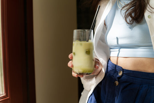 Woman ready to drink refreshing iced matcha latte. Summer vibes background aesthetic