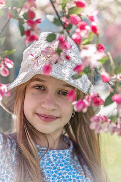 Smiling Girl in White Lace Hat Surrounded by Pink Cherry Blossoms