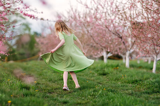 Girl twirling in blooming spring orchard