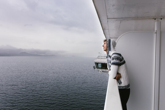 Young adult looking out on balcony on cruise ship on pacific ocean