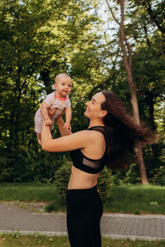 Young mother playing with baby outdoors in summer park