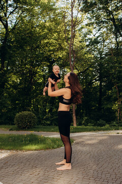 Sporty mother holding baby in park during outdoor workout