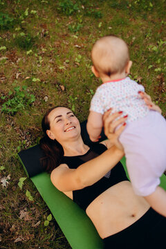 Mother exercising with baby outdoors on yoga mat