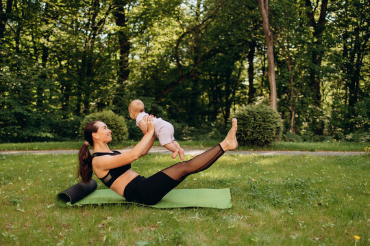 Sporty mother exercising with baby on yoga mat outdoors