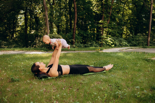 Mother lifting baby during outdoor fitness workout in park