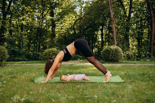 Mother practicing yoga near baby outdoors in park