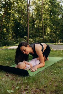 Happy mother spending time with baby on yoga mat outdoors
