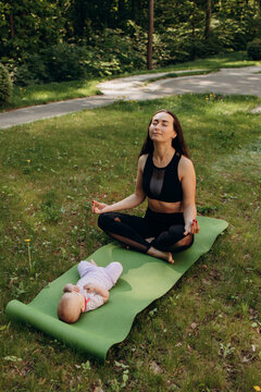 Young mother meditating near baby outdoors in park