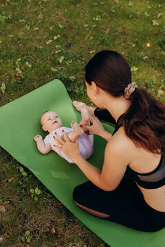 Mother playing with baby on yoga mat outdoors