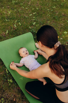 Mother interacting with baby on yoga mat outdoors