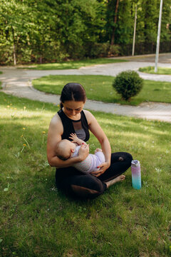 Mother breastfeeding her baby after outdoor workout in park