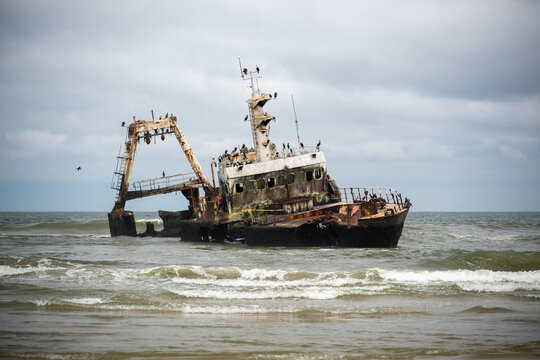 Rusted Shipwreck On Sandy Beach Under Brooding Sky
