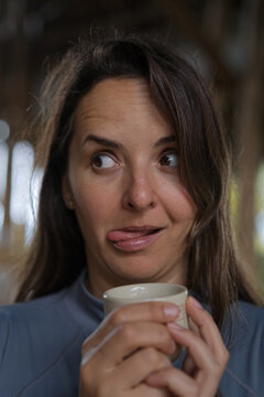 Funny woman with coffee cup sticking out tongue, Munduk, Bali