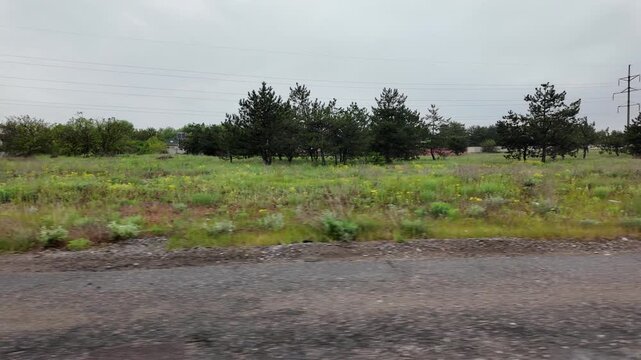 Slow-motion video shot from a moving silver car's perspective on a bumpy asphalt road in the countryside. The car's body 