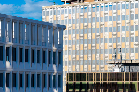Lyon office facade with blue geometric fins beside a building of windows, shaping urban architecture into a crisp business exterior in daylight