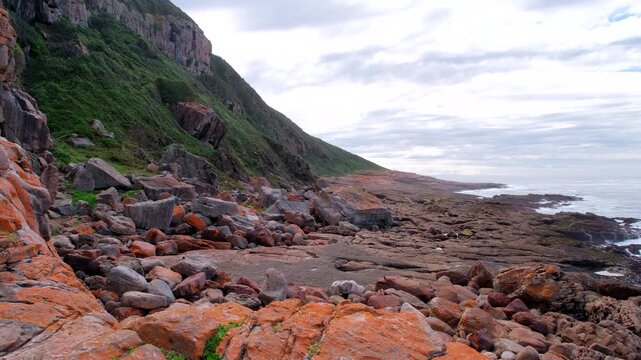 Orange lichen colored coastal rocks along rugged Robberg hiking trail in Plett