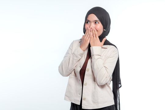 Young woman in hijab covers mouth in surprise