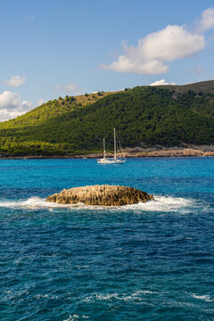 Sailing yacht near Cala Agulla beach in Mallorca surrounded by turquoise sea and coastal scenery. Popular Mediterranean travel destination.