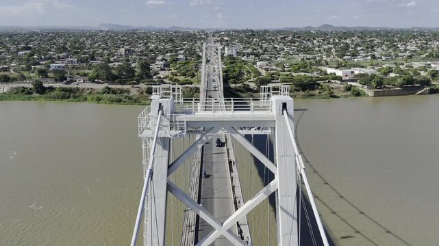 Drone flies northeast from middle of Samora Machel Bridge over Zambezi River to Matundo side on a sunny day in Tete, Mozambique