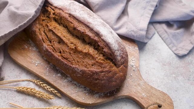 Freshly baked rye bread loaf resting on wooden board