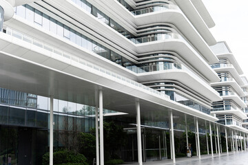 Fototapeta premium Modern Futuristic Office Building with Curved White Facade and Glass Windows in Urban Setting
